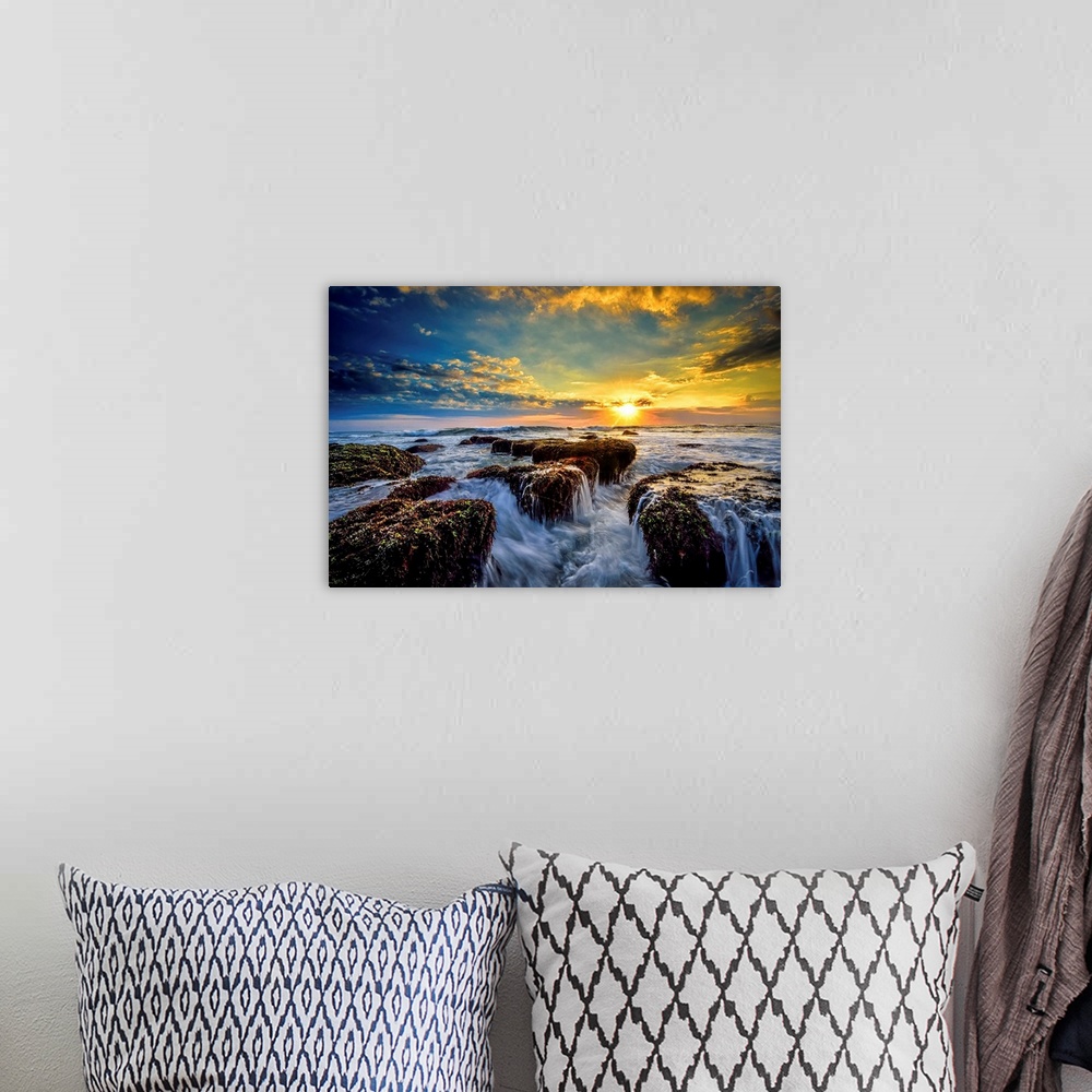 A bohemian room featuring Dramatic clouds of sunset hanging over a seascape with rocky shoreline in the foreground.