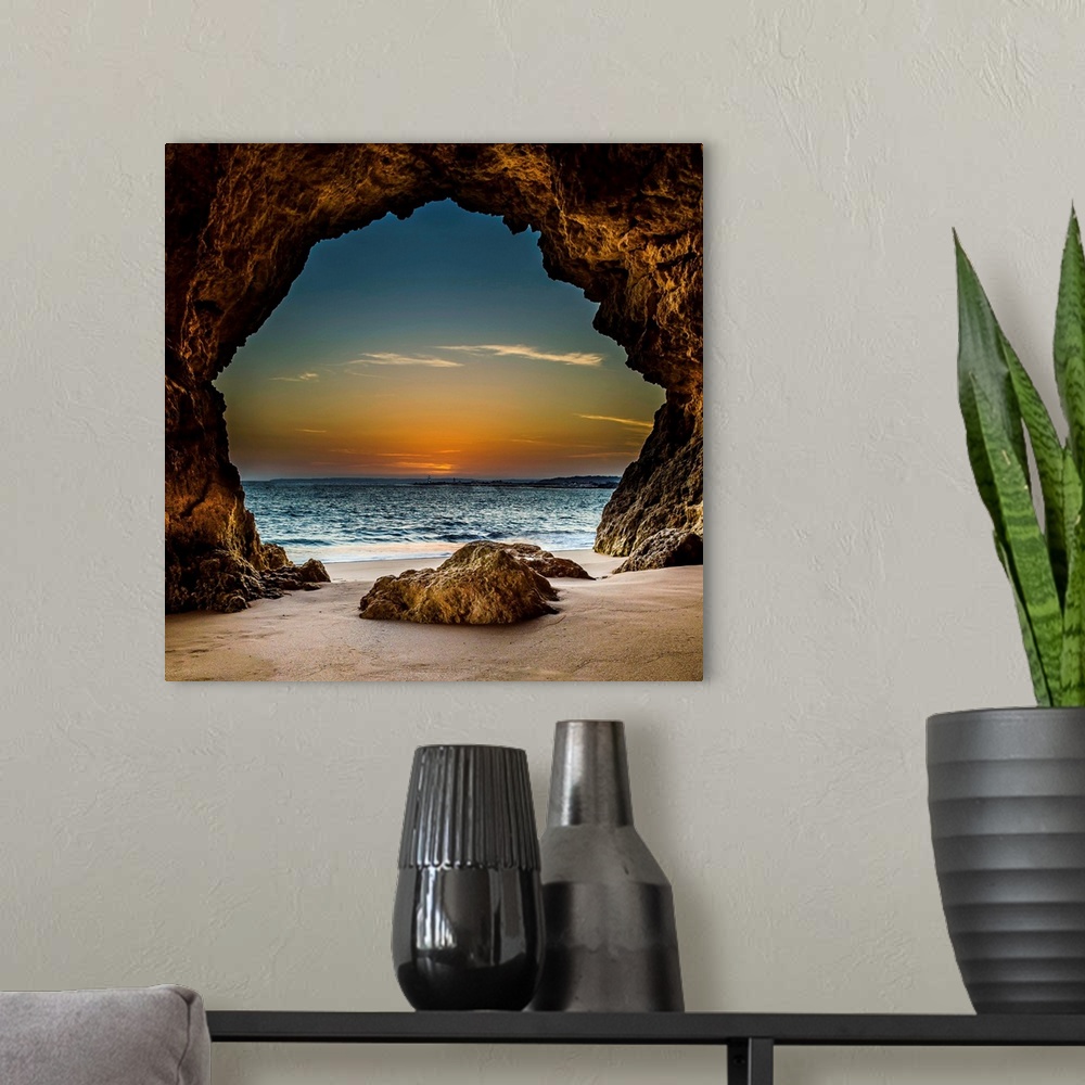 A modern room featuring View from inside a cave on the beach, looking out at the sunset, Ferragudo, Portugal.