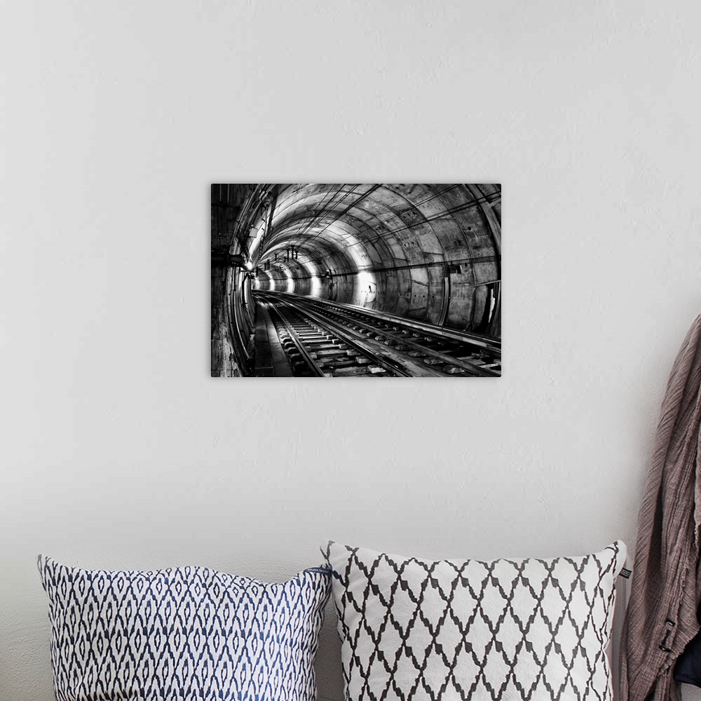 A bohemian room featuring Train tracks in an underground tunnel, in black and white.