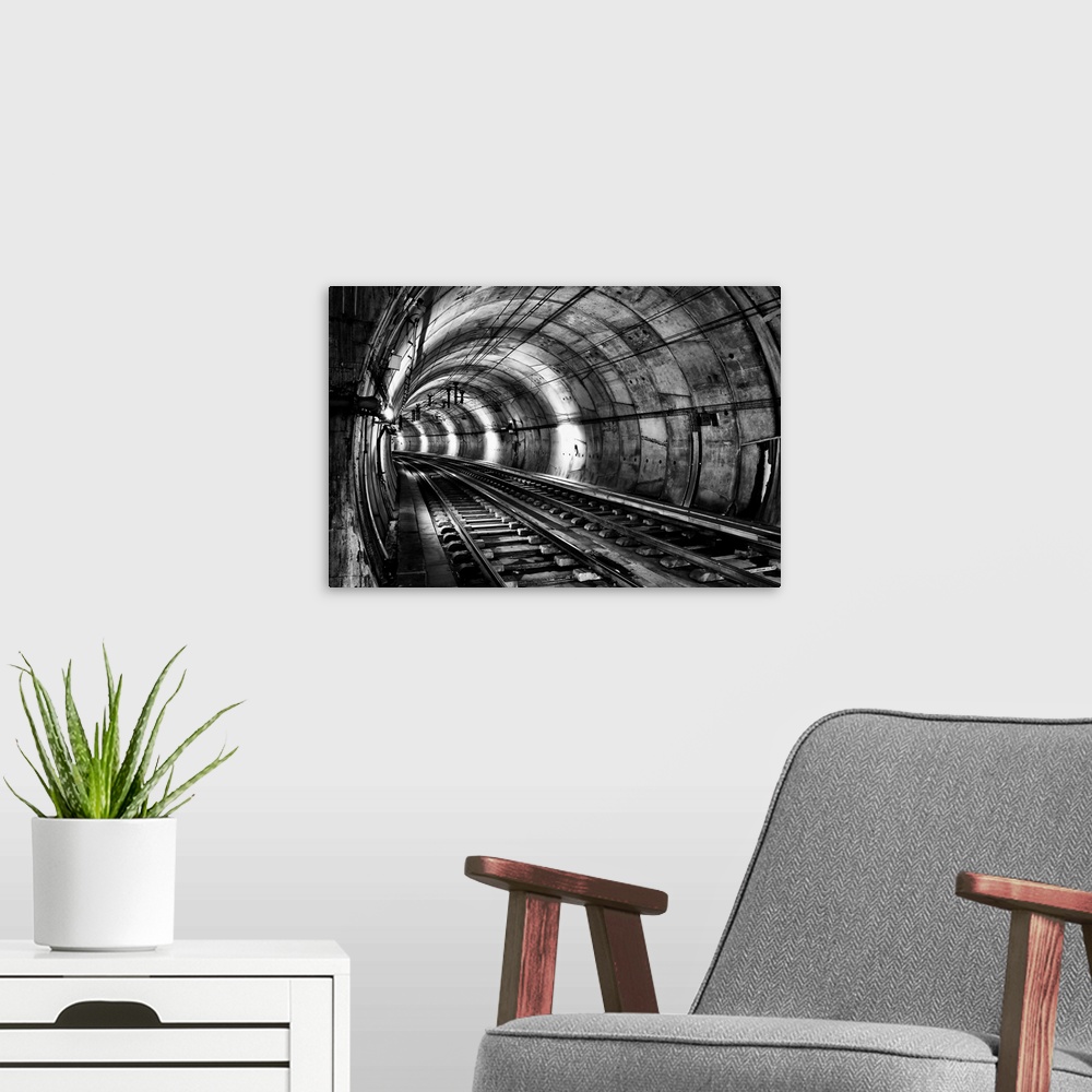 A modern room featuring Train tracks in an underground tunnel, in black and white.