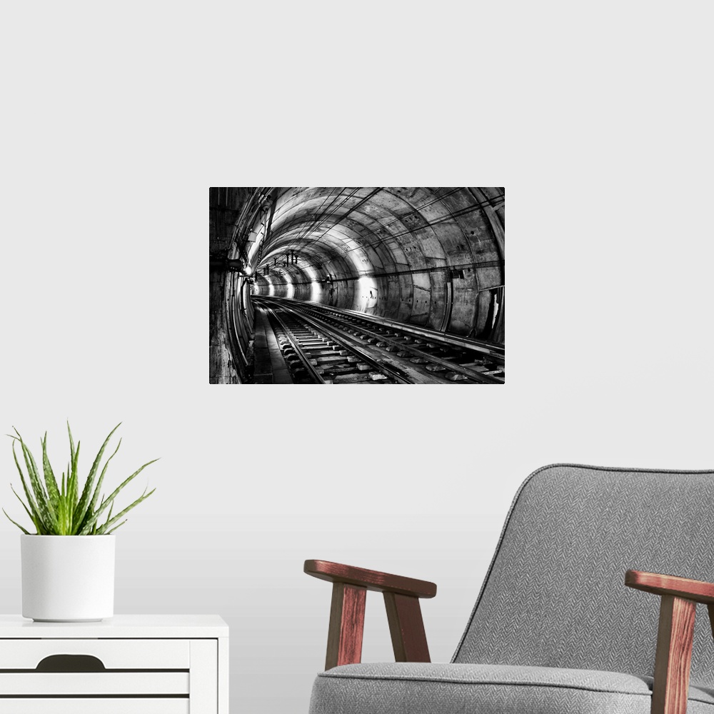 A modern room featuring Train tracks in an underground tunnel, in black and white.