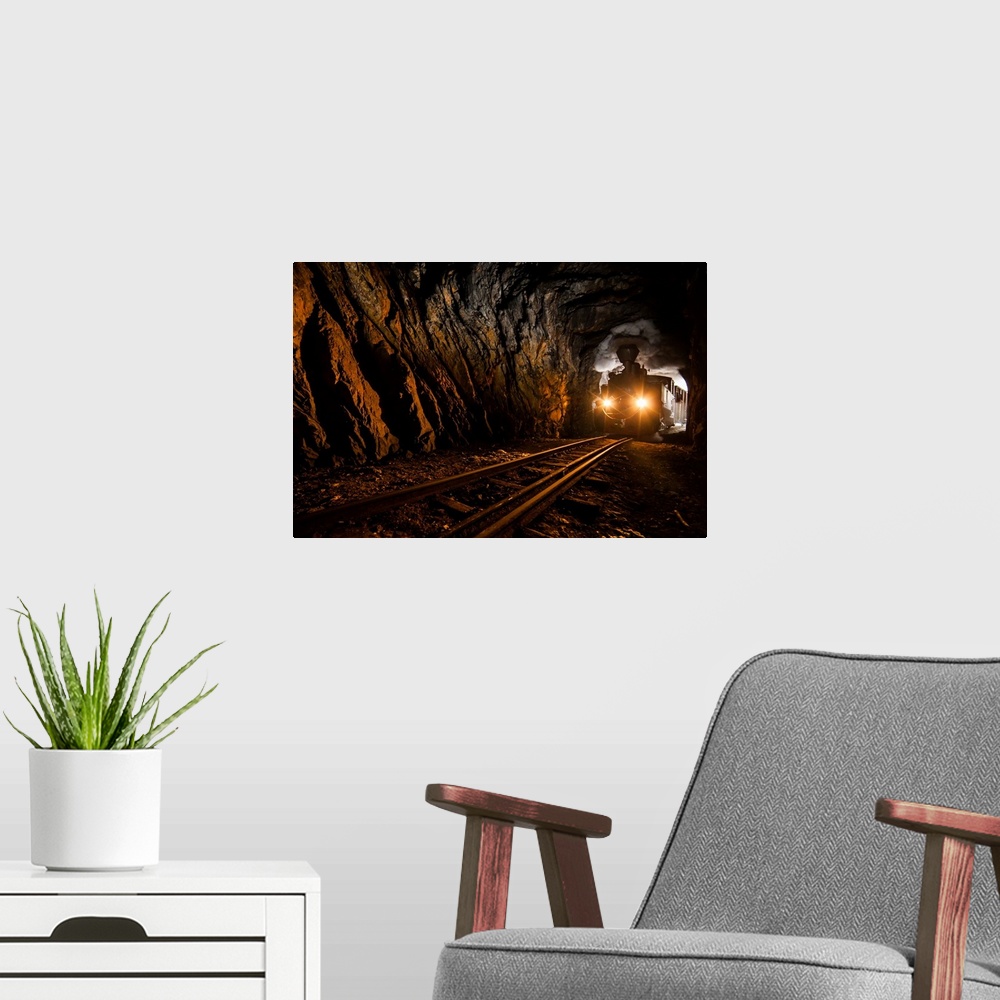 A modern room featuring Silhouette of a train barreling through a tunnel, with smoke pouring from the stack.
