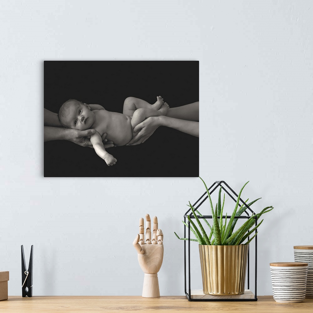 A bohemian room featuring A couple holding a newborn baby in their hands.