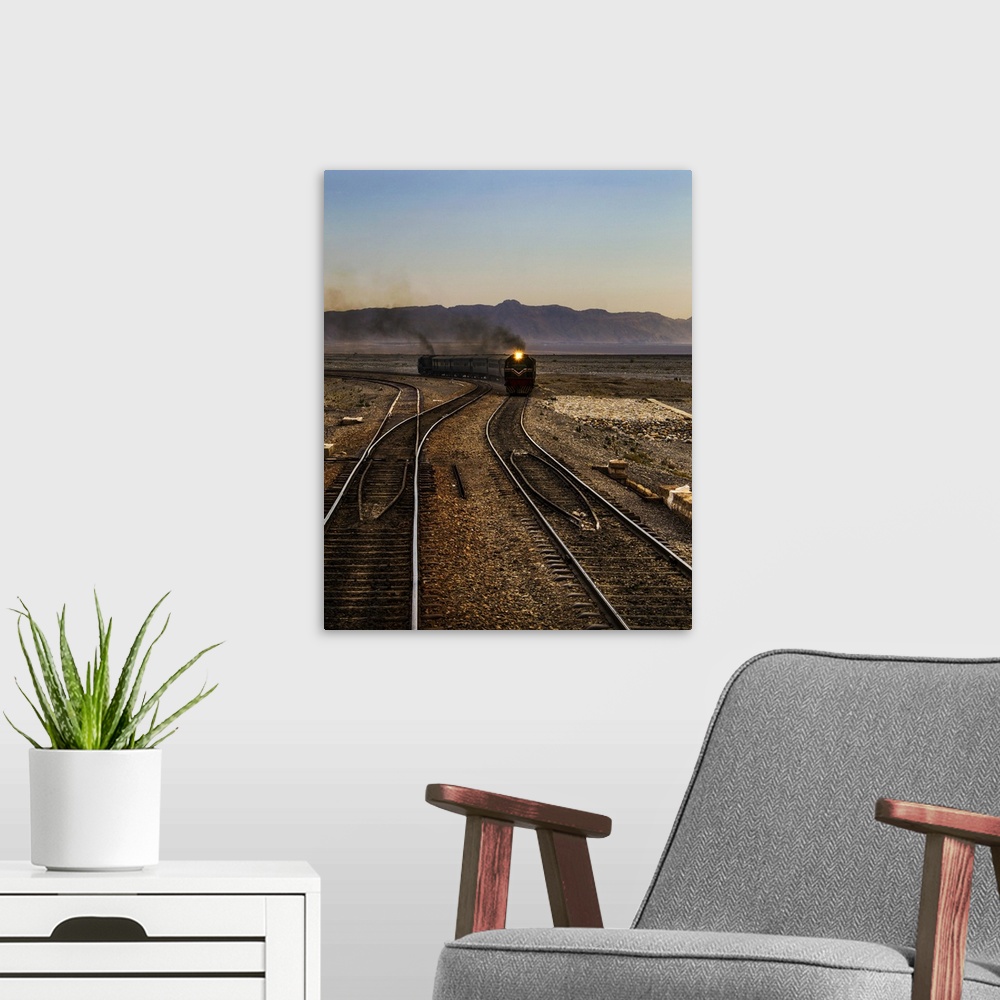 A modern room featuring A train approaching on the railroad tracks in the late afternoon.