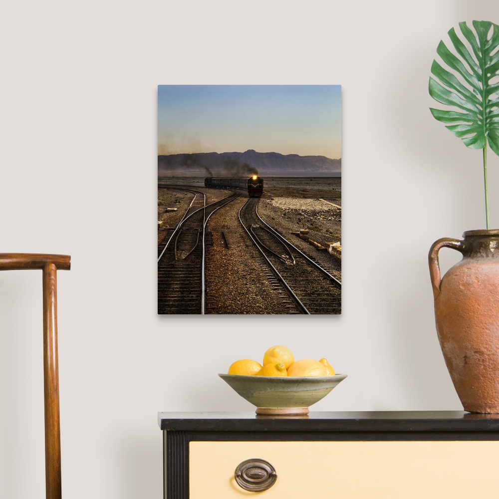A traditional room featuring A train approaching on the railroad tracks in the late afternoon.