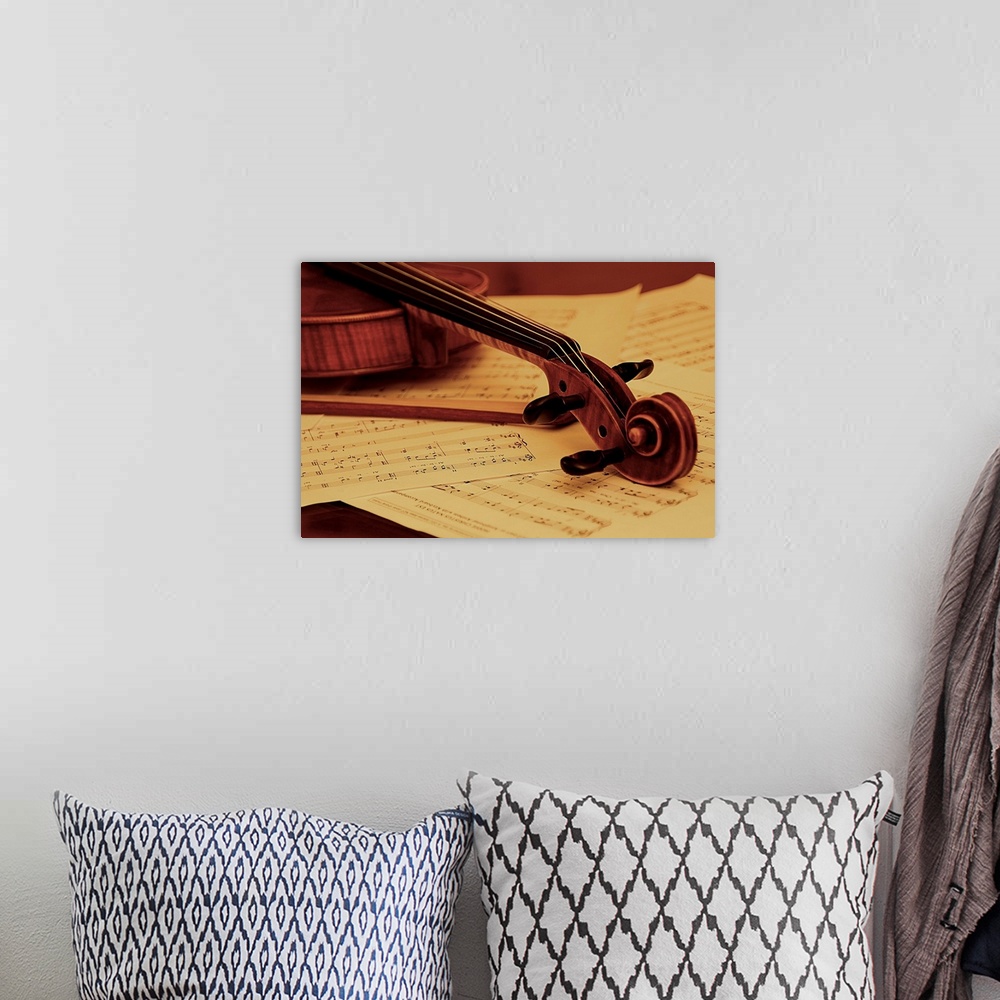 A bohemian room featuring The head of a violin resting on sheet music.
