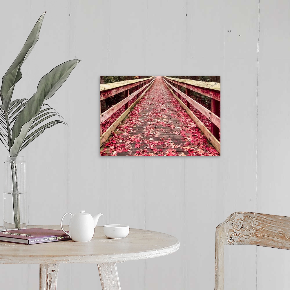 A farmhouse room featuring A wooden walkway covered with red fallen leaves.