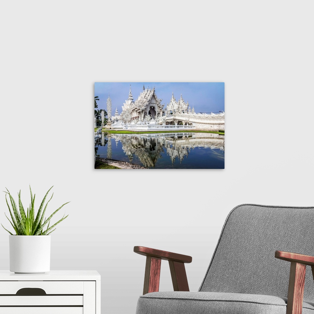 A modern room featuring Beautiful Wat Rong Khun temple on the water, Thailand.