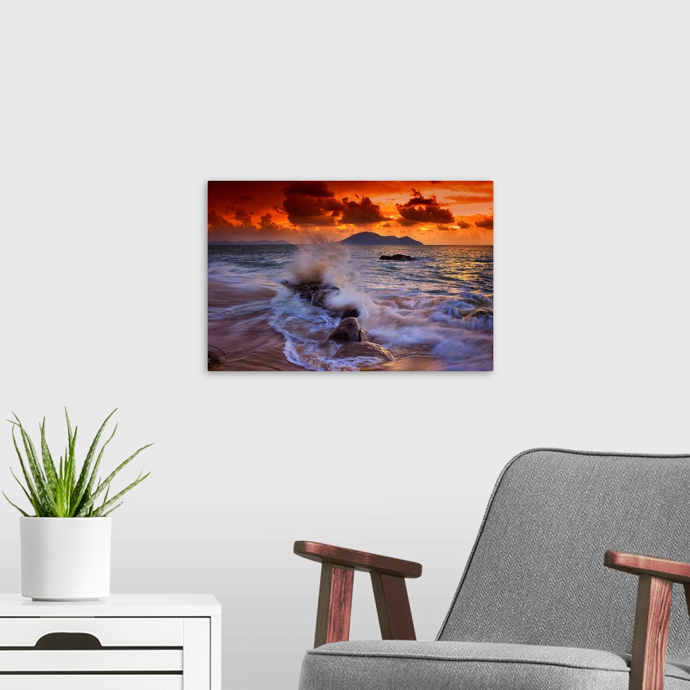 A modern room featuring Waves crashing onto rocks on the beach at sunset.