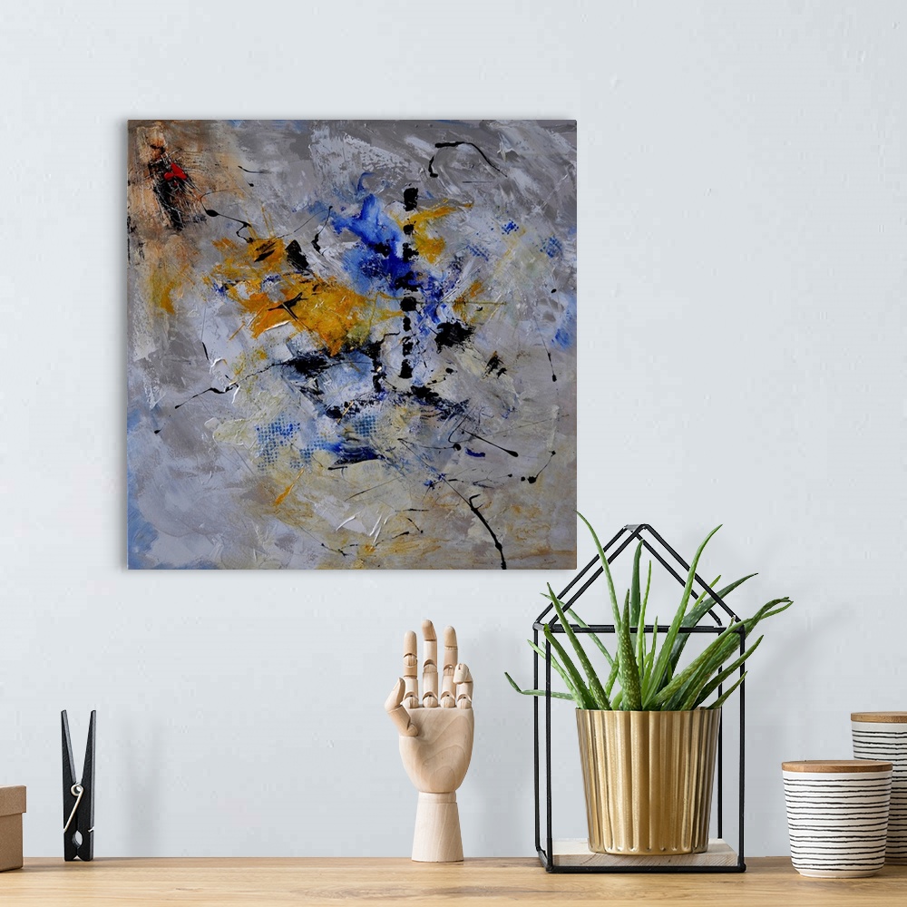 A bohemian room featuring A square abstract painting in dark shades of gray, blue, white and yellow with splatters of paint...