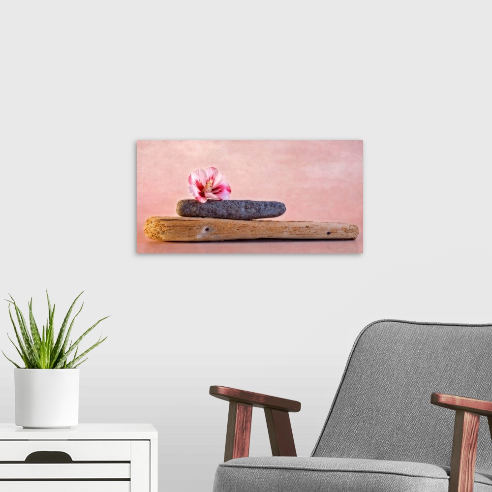A modern room featuring Decorative artwork that has a plank of wood with a stone on top of it and a hibiscus flower on to...