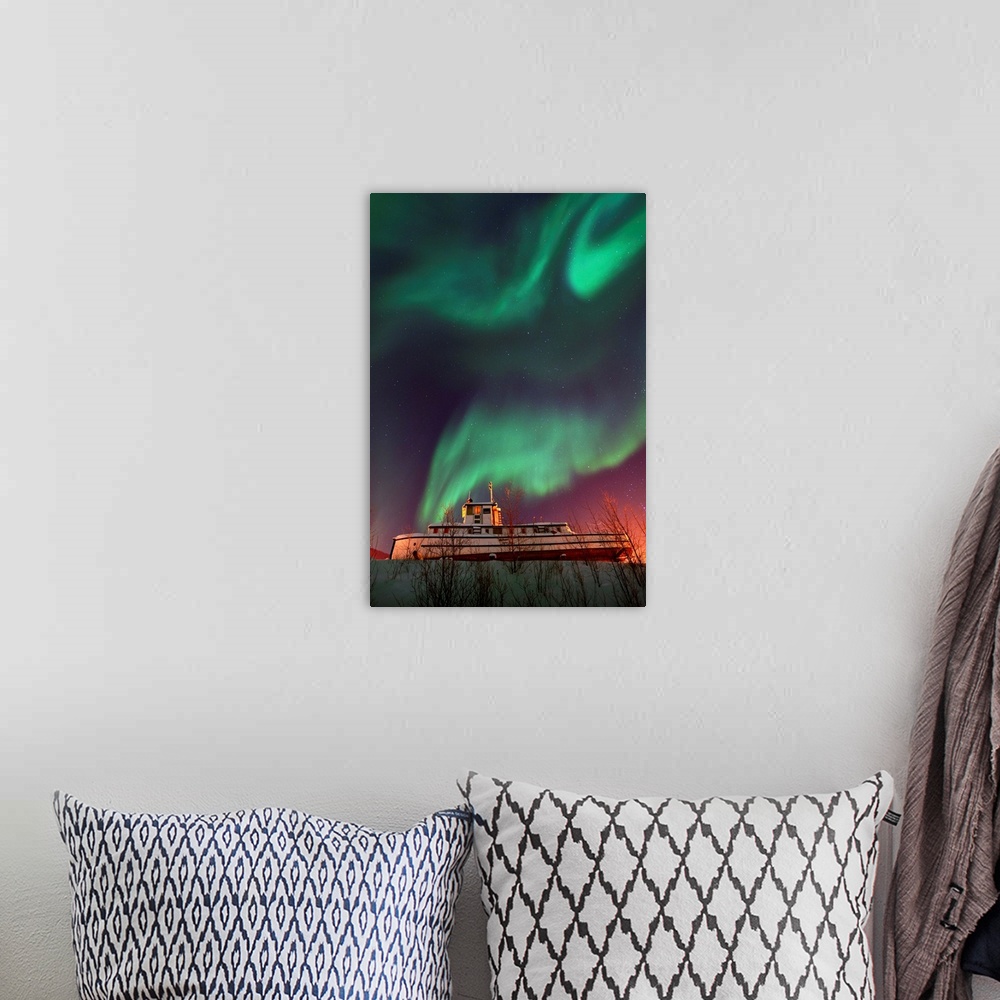 A bohemian room featuring Old steamboat under a sky full of dancing northern lights. Located in Dawson City, Yukon, Canada