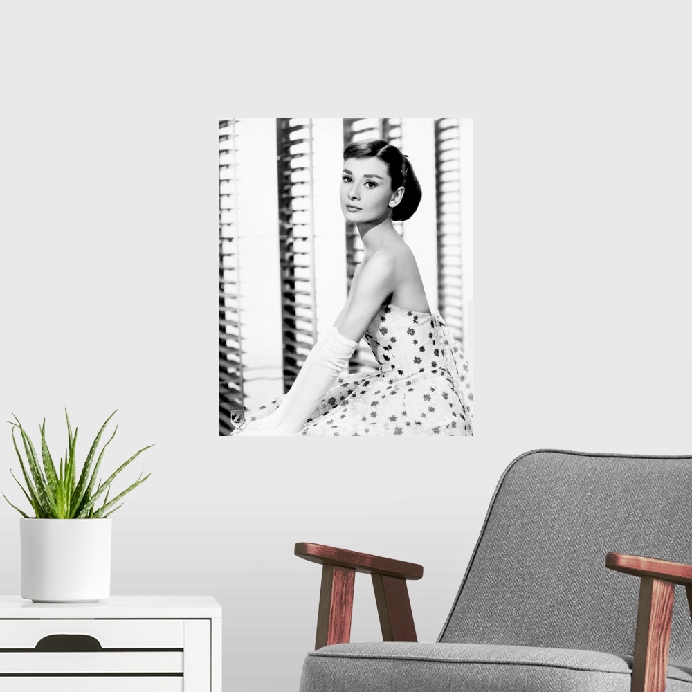 A modern room featuring Big, vertical photograph of a side view of Audrey Hepburn sitting in a floral dress and long, whi...