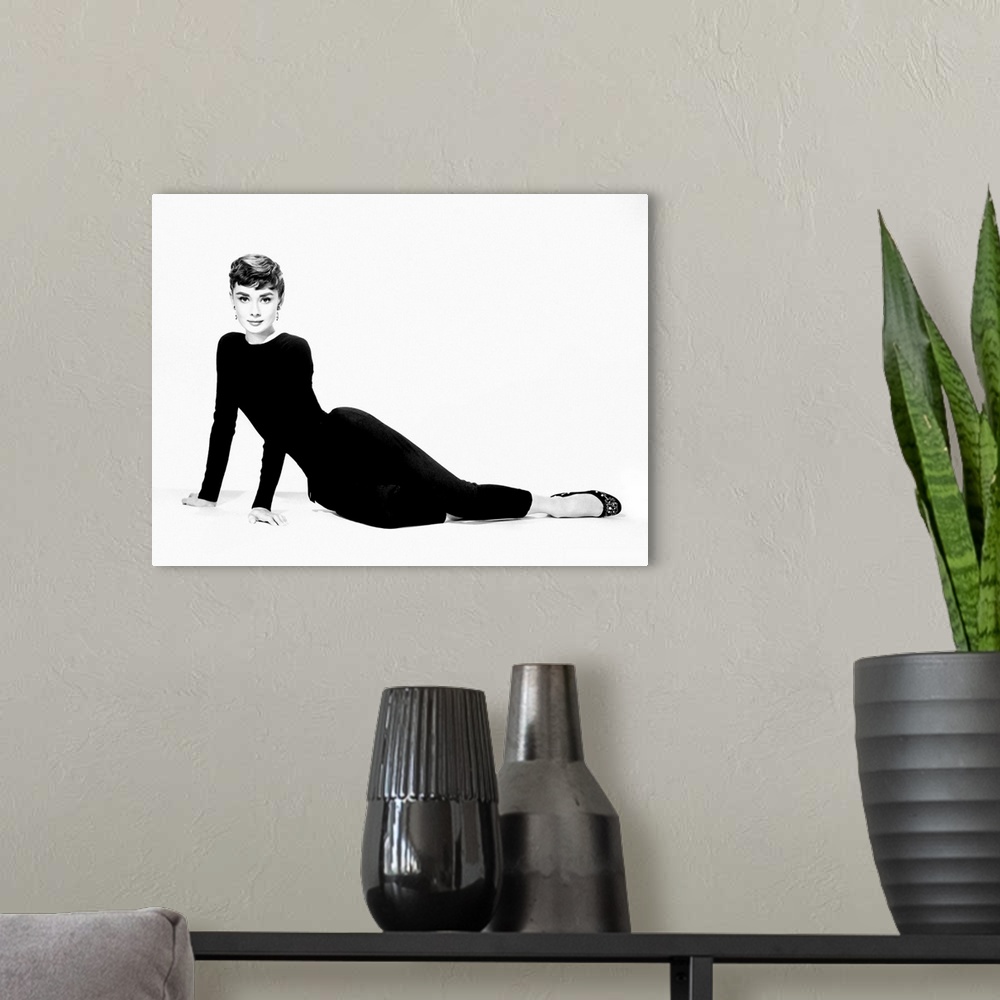 A modern room featuring A large piece of artwork in black and white of Audrey Hepburn sitting on her hip and both arms st...