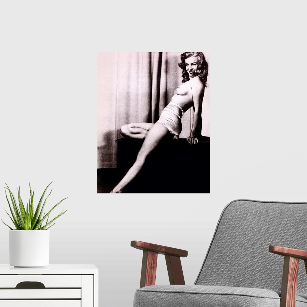 A modern room featuring Boudoir photo of Marilyn Monroe topless and leaning back on a stand in front of a curtain, smilin...