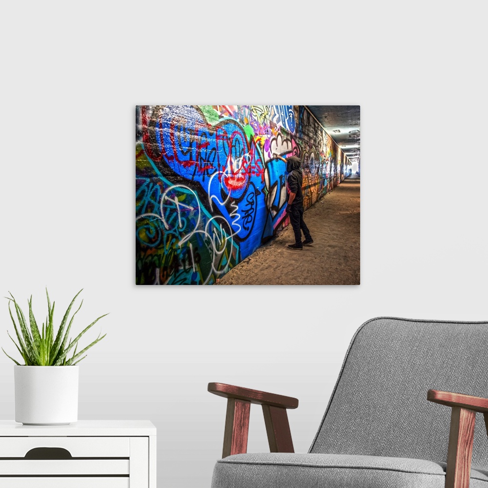 A modern room featuring A graffiti artist adds to a mural in the Krog Street Tunnel, which connects Inman Park and Cabbag...