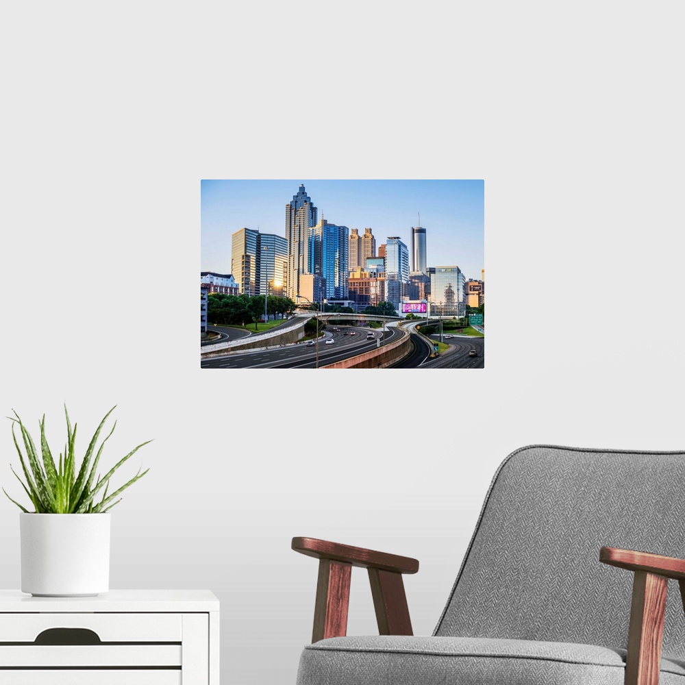 A modern room featuring Morning sunlight reaching the skyscrapers of Atlanta, Georgia, see from the freeway.