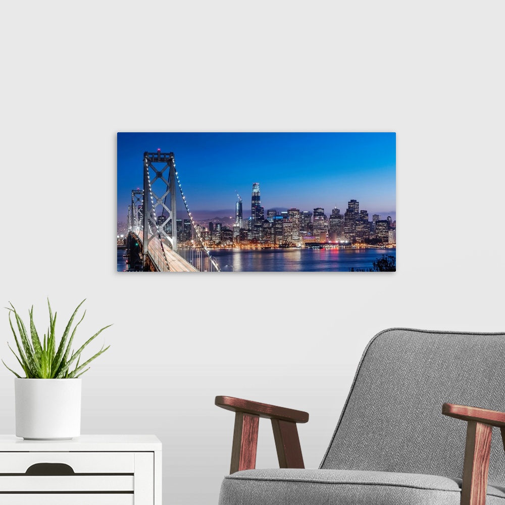 A modern room featuring Photograph of the Bay Bridge and the San Francisco skyline lit up at dusk.