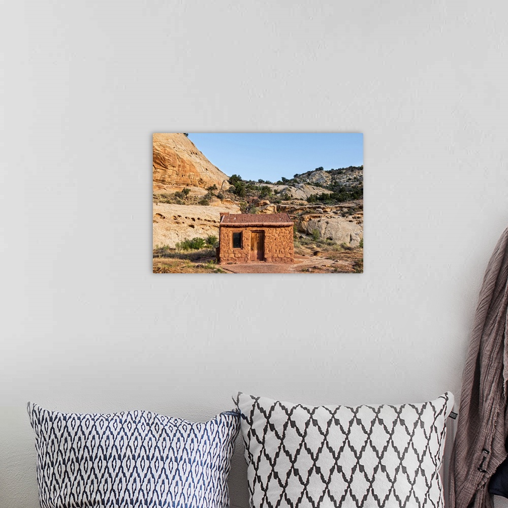 A bohemian room featuring Behunin Cabin with the cliffs of the Waterpocket Fold overlooking it at Capitol Reef National Par...