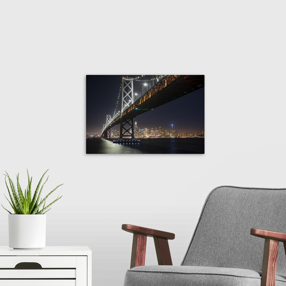 A modern room featuring Photograph from below the Bay Bridge at night with the San Francisco skyline lit up in the backgr...