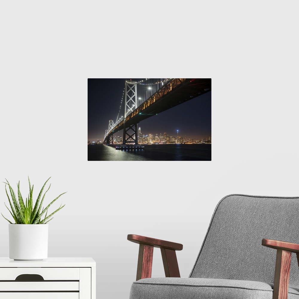A modern room featuring Photograph from below the Bay Bridge at night with the San Francisco skyline lit up in the backgr...