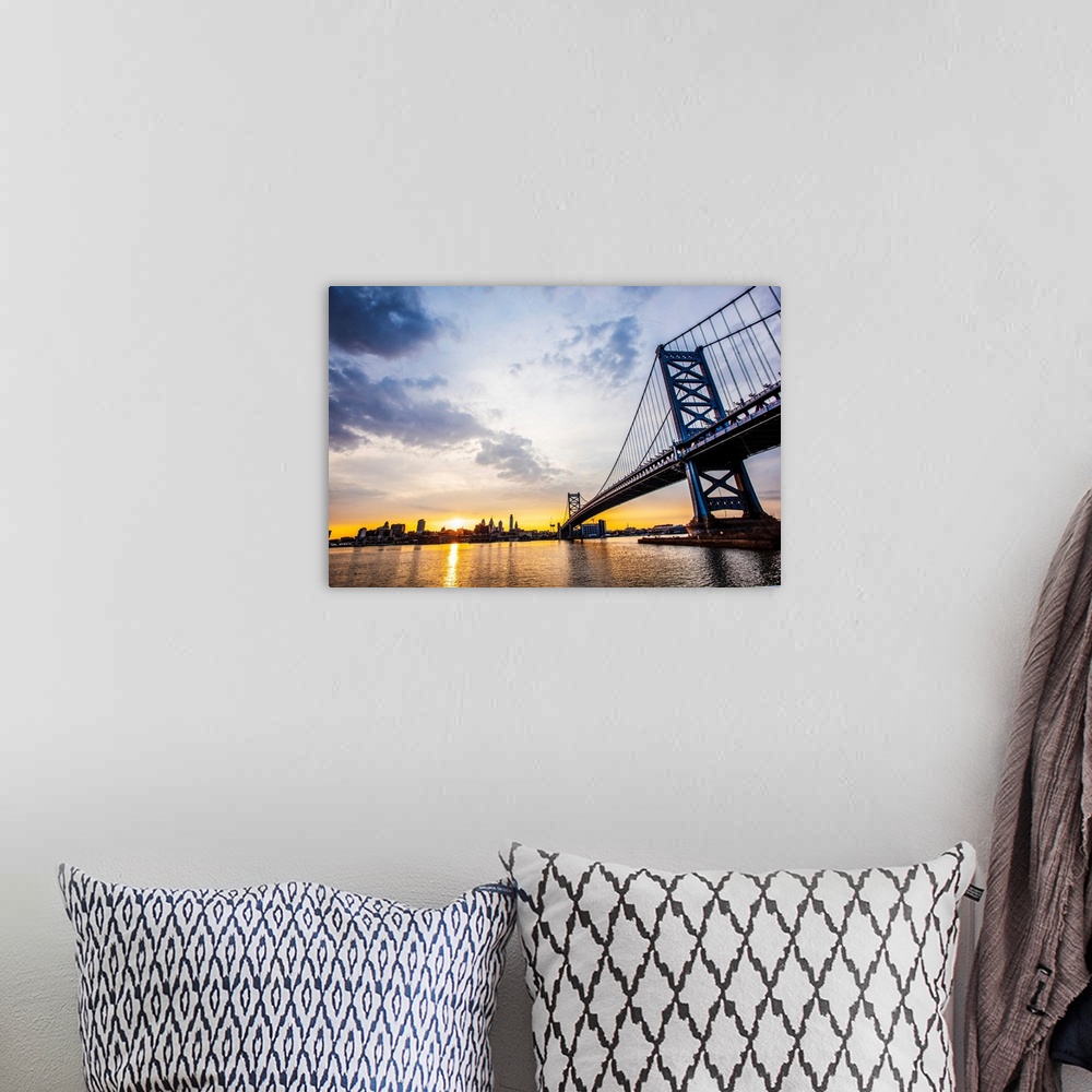 A bohemian room featuring The sun sets with dramatic clouds above Philadelphia's Ben Franklin Bridge.