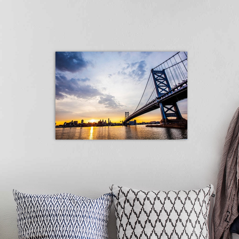 A bohemian room featuring The sun sets with dramatic clouds above Philadelphia's Ben Franklin Bridge.
