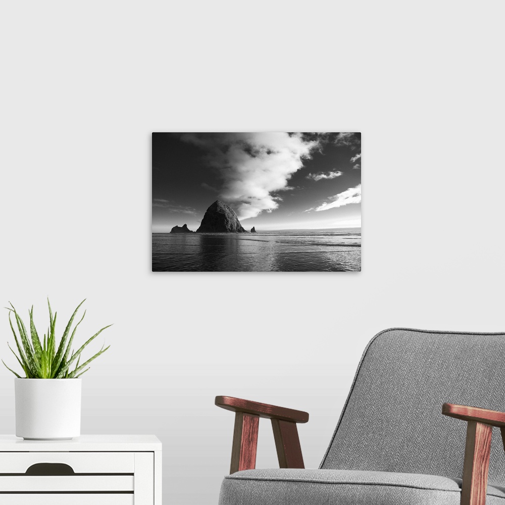A modern room featuring Black and white photograph of Haystack Rock with rippling waters.