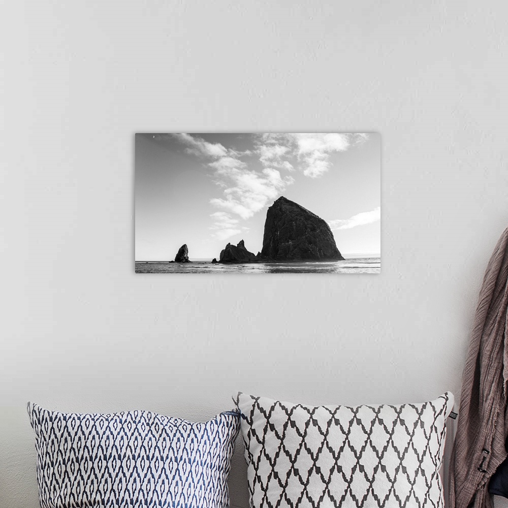 A bohemian room featuring Black and white photograph of Haystack Rock with the moon in the top corner.