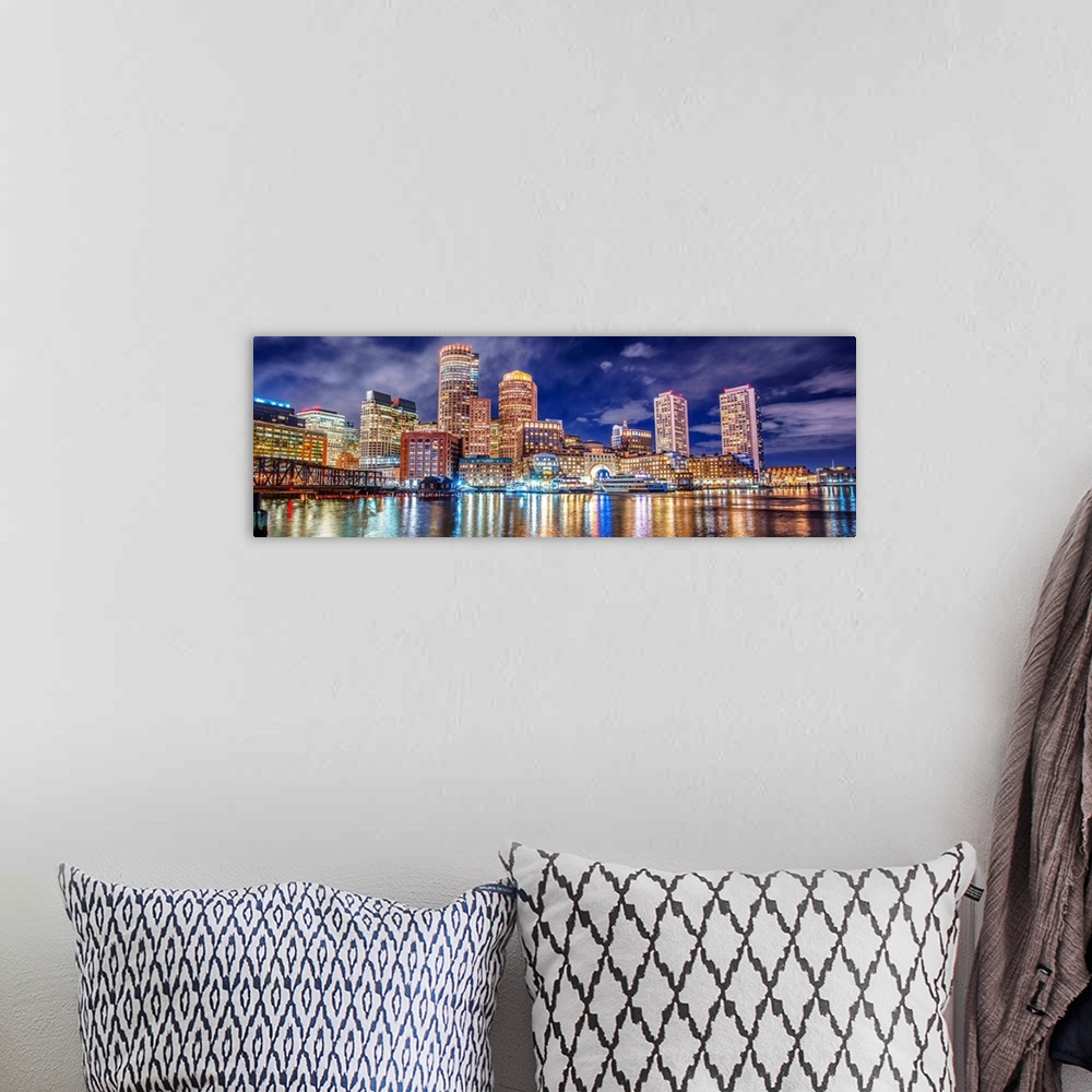 A bohemian room featuring Panoramic view of the Boston City skyline at night, with lights reflected in the water.