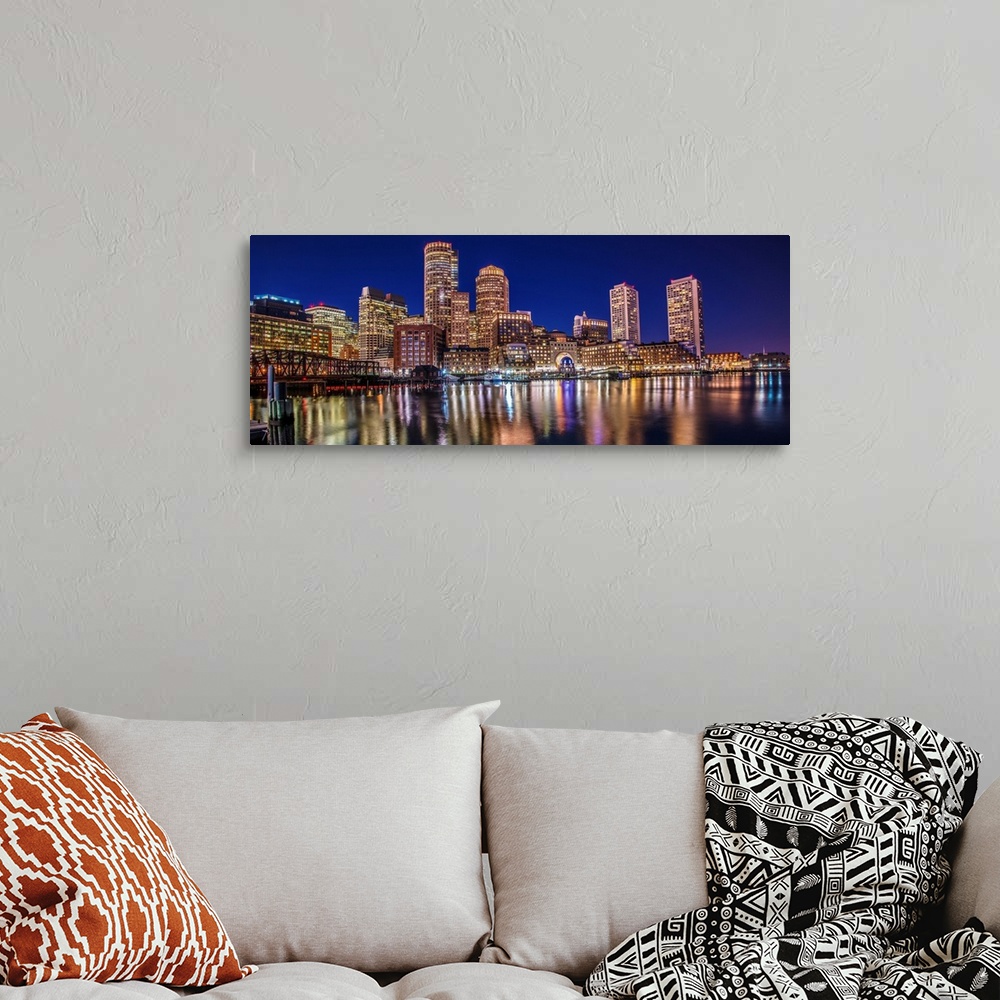 A bohemian room featuring Panoramic view of the Boston City skyline at night, with lights reflected in the water.