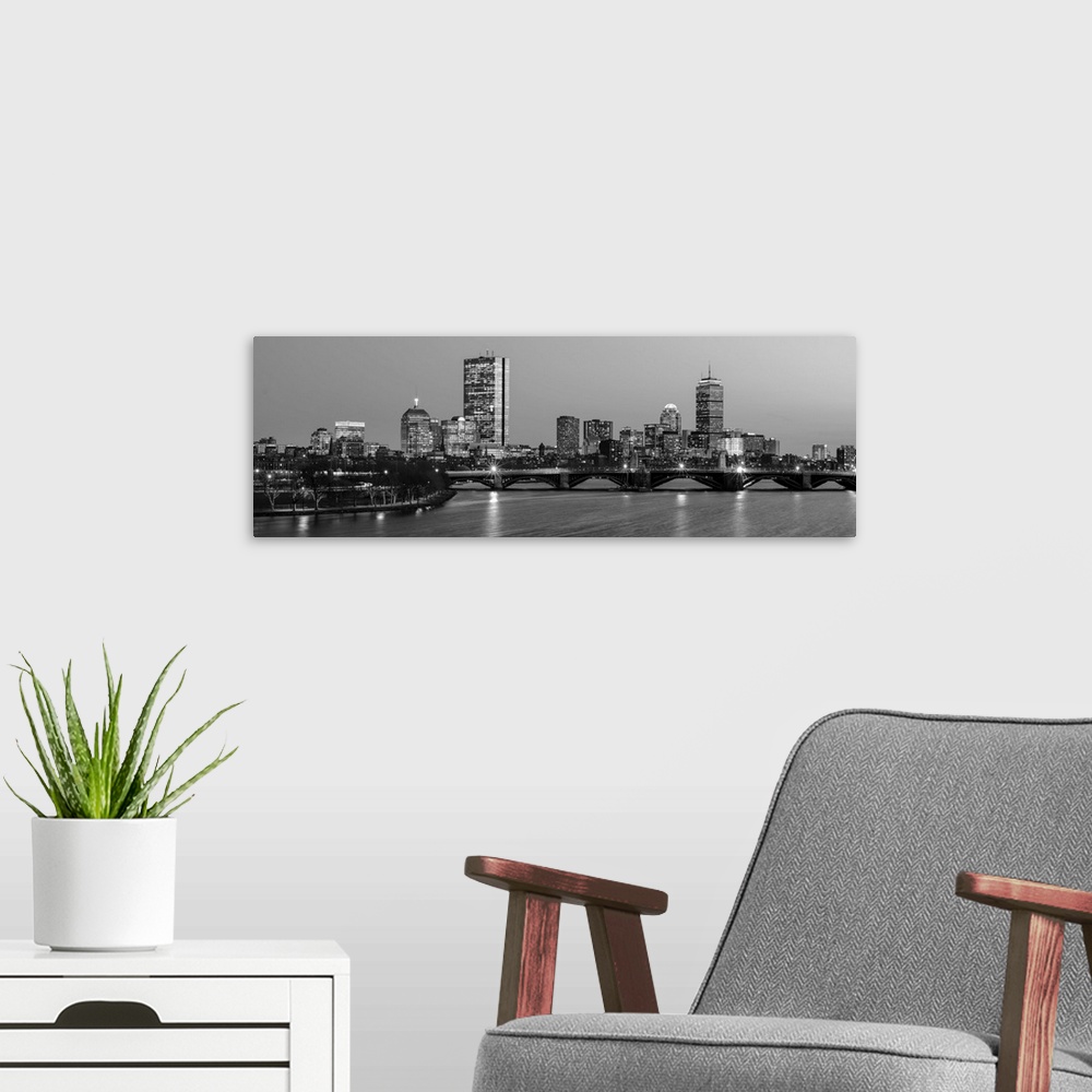 A modern room featuring Panoramic view of the Boston City skyline illuminated at night, with the Longfellow Bridge in the...