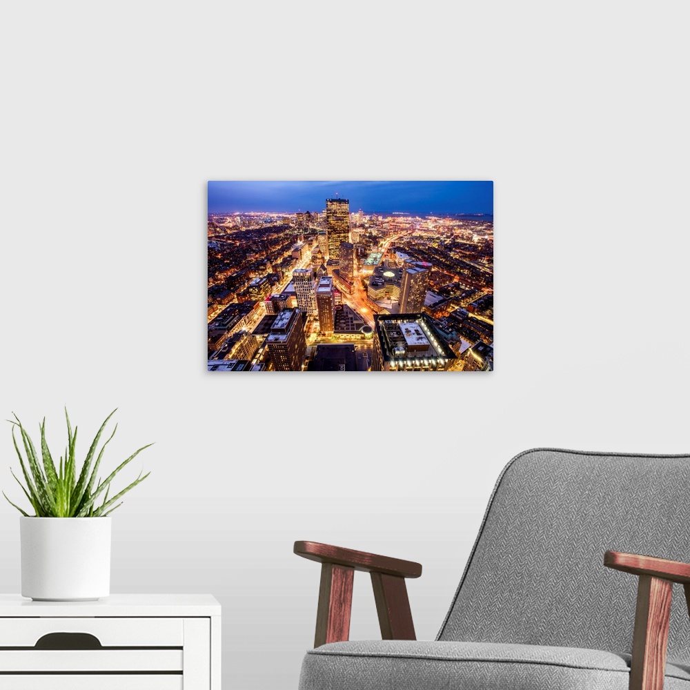 A modern room featuring Aerial view of the city of Boston, Massachusetts, lit up at night.