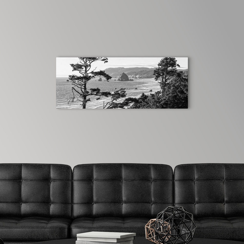 A modern room featuring Black and white panoramic landscape photograph of Cannon Beach through the trees with Haystack Ro...