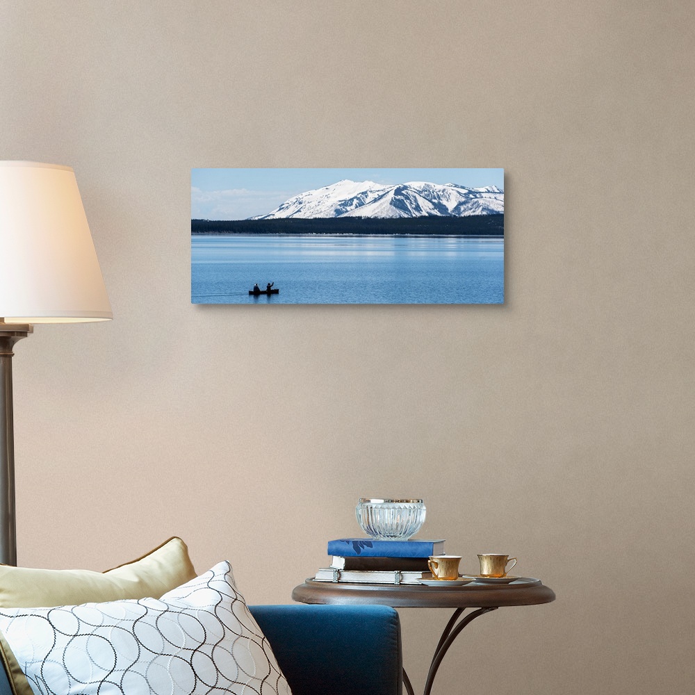 A traditional room featuring Two people canoeing on Jackson Lake with the snow covered Grand Teton mountains in the background.