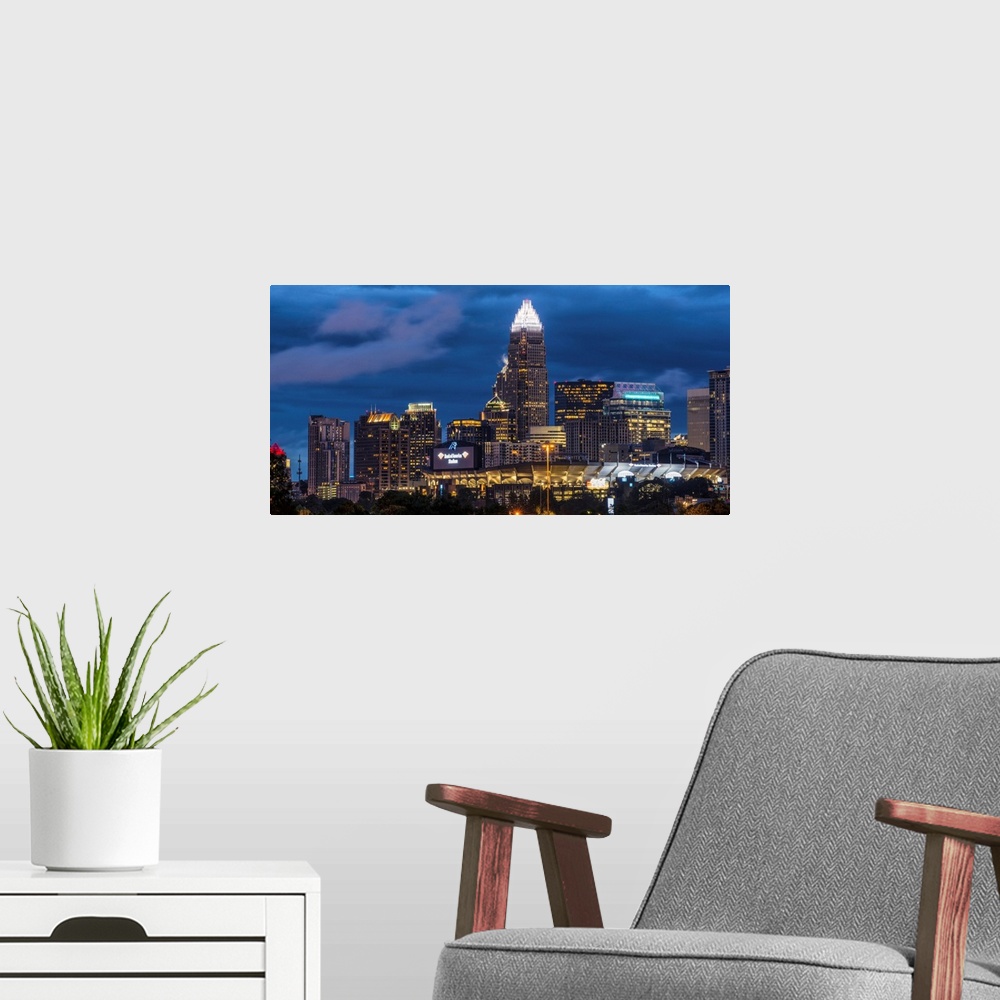 A modern room featuring A horizontal image of the Charlotte, North Carolina city skyline at night.