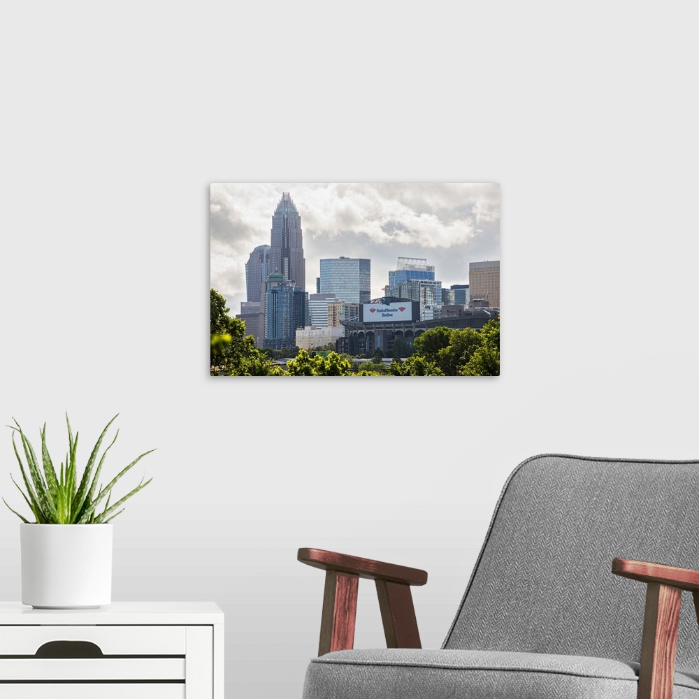 A modern room featuring A forest of trees in the foreground of the Charlotte North Carolina city skyline