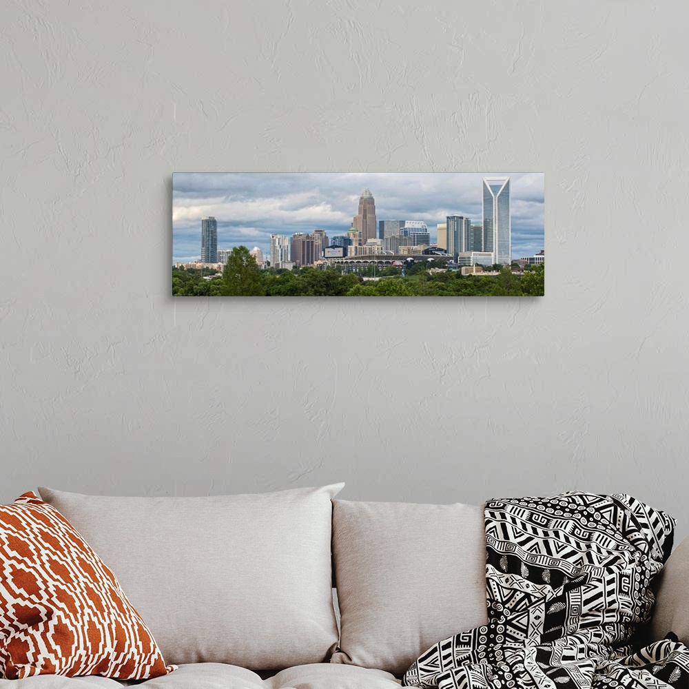 A bohemian room featuring A forest of trees in the foreground of the Charlotte North Carolina city skyline.
