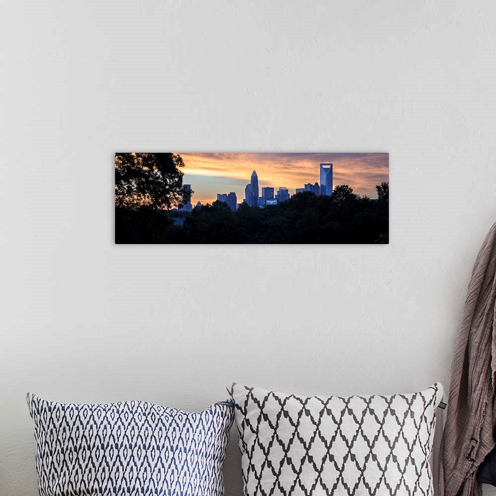 A bohemian room featuring The city of Charlotte, North Carolina at sunset with a forest of trees in the foreground.