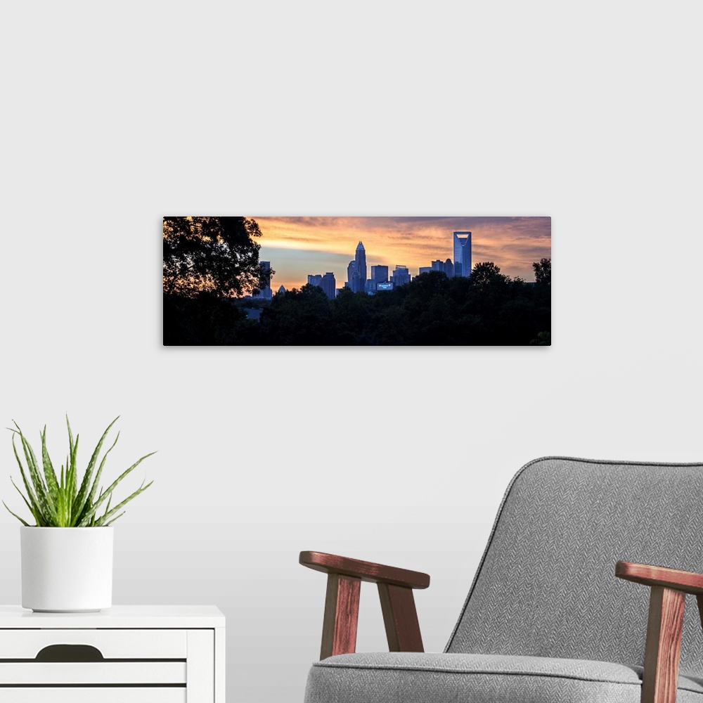 A modern room featuring The city of Charlotte, North Carolina at sunset with a forest of trees in the foreground.