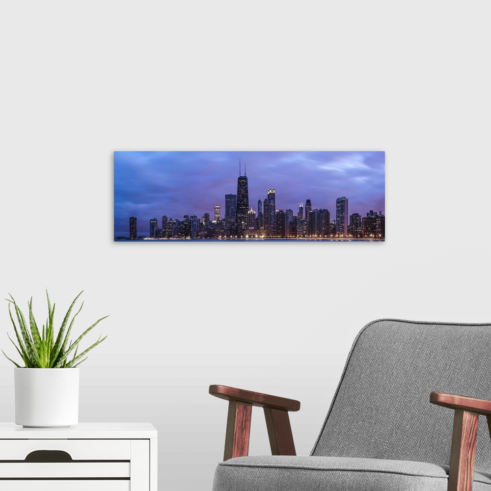 A modern room featuring Panoramic view of the Chicago city skyline illuminated in the early evening, seen from across the...