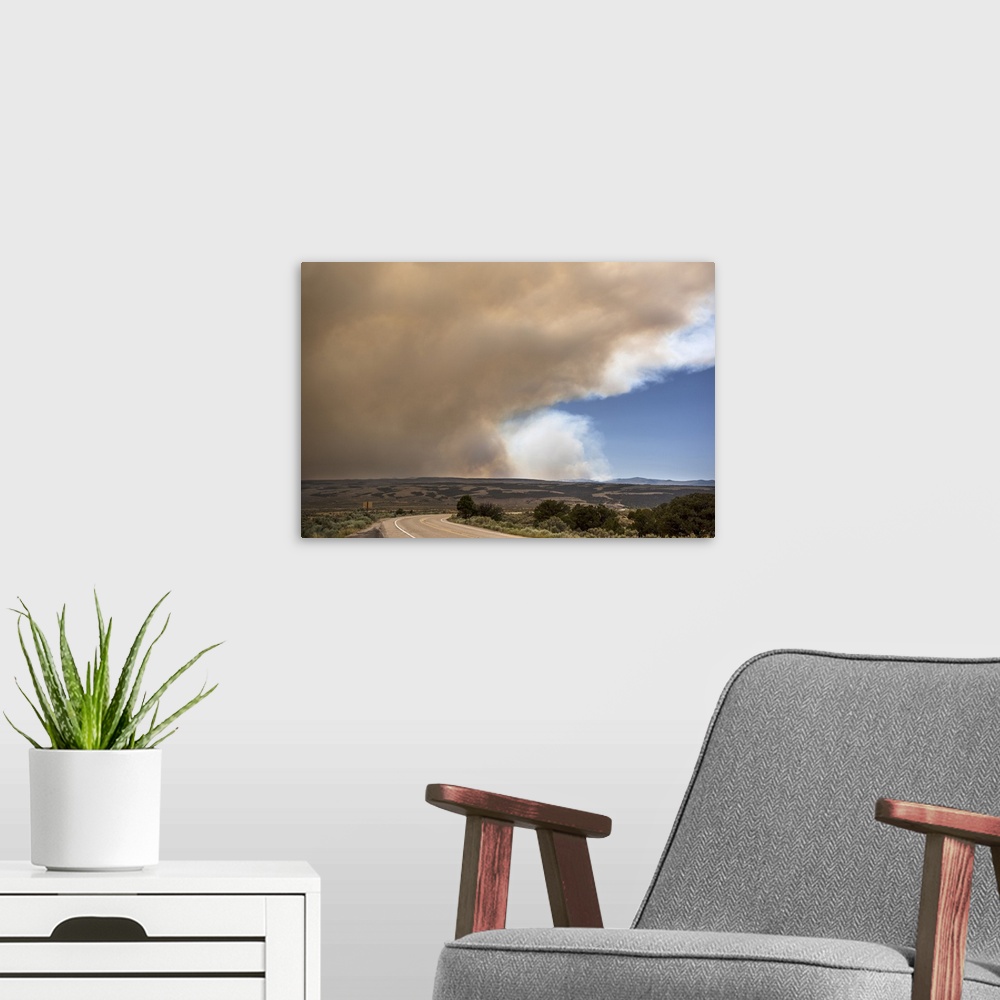 A modern room featuring Massive billowing smoke clouds from the Brian Head forest fire in the sky over the Utah landscape.
