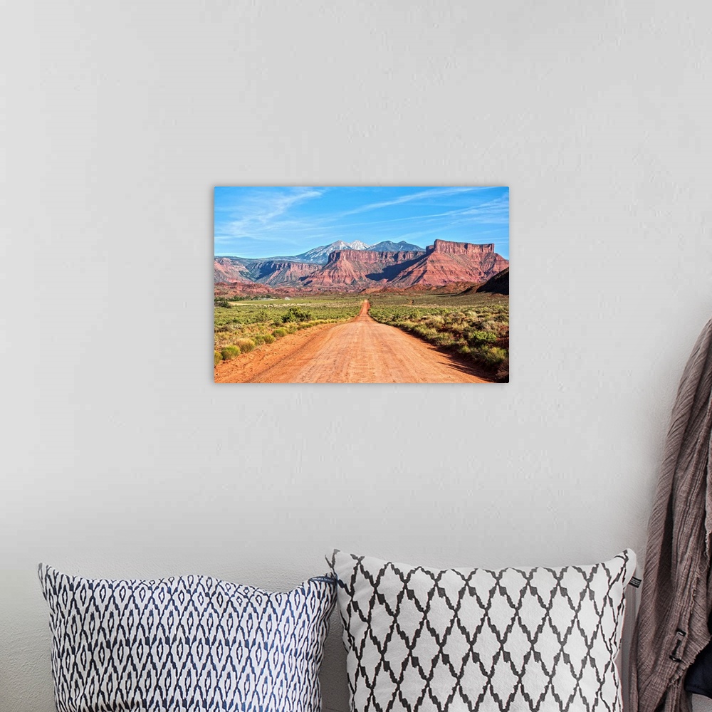 A bohemian room featuring A dirt road leading towards the sandstaone cliffs and La Sal Mountains in Arches National Park, M...
