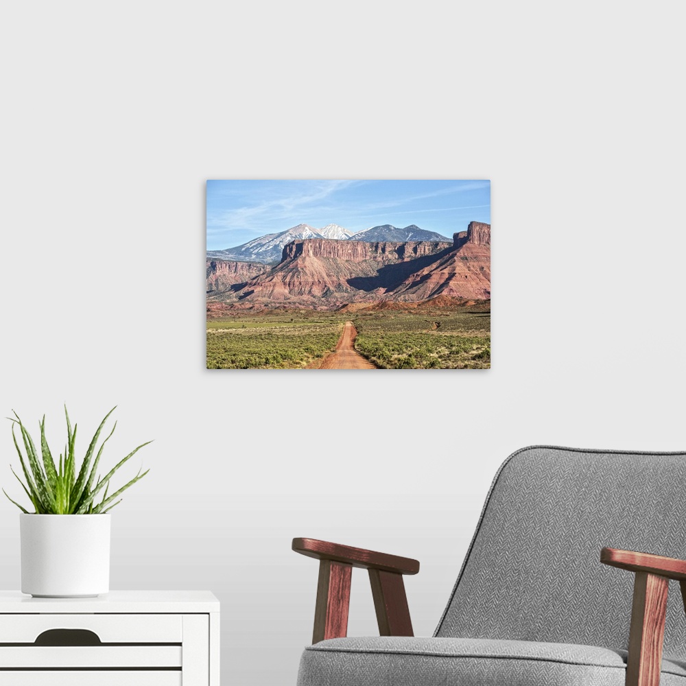 A modern room featuring A dirt road leading towards the sandstaone cliffs and La Sal Mountains in Arches National Park, M...