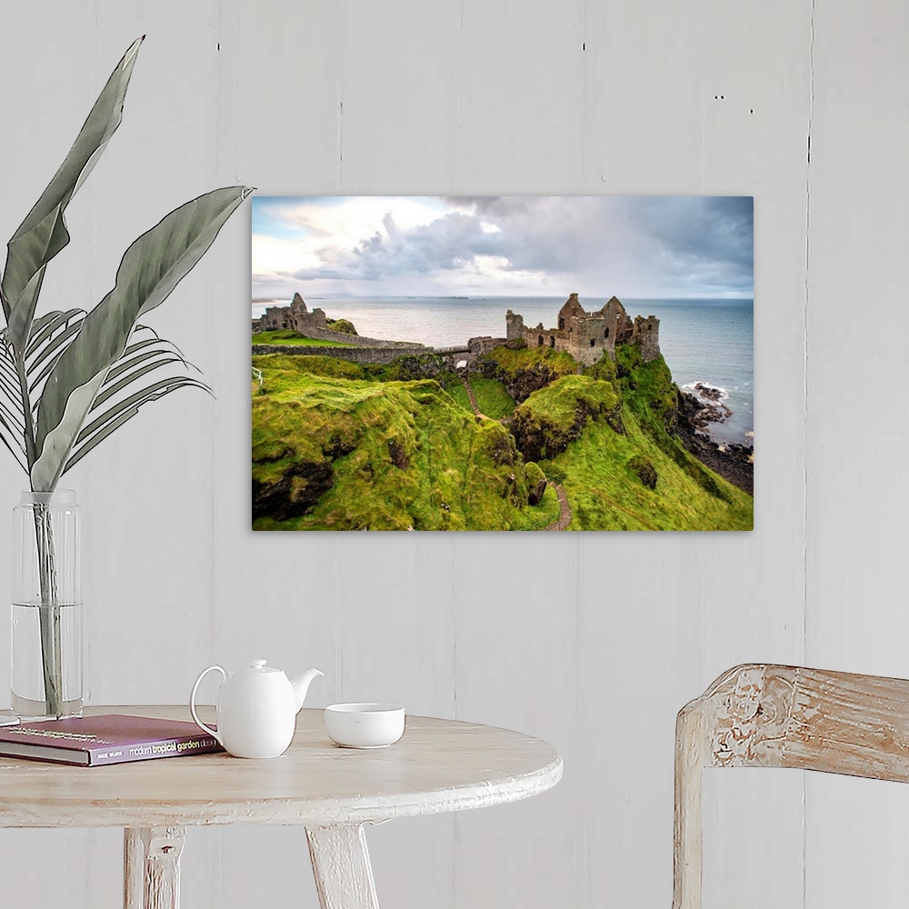 A farmhouse room featuring Landscape photograph of Dunluce Castle next to the ocean, taken from a higher point.