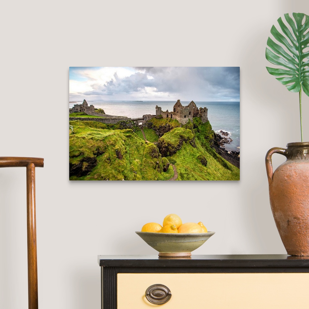 A traditional room featuring Landscape photograph of Dunluce Castle next to the ocean, taken from a higher point.