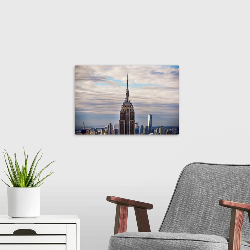 A modern room featuring Top view of the Empire State Building Broadcast Tower against dramatic clouds.
