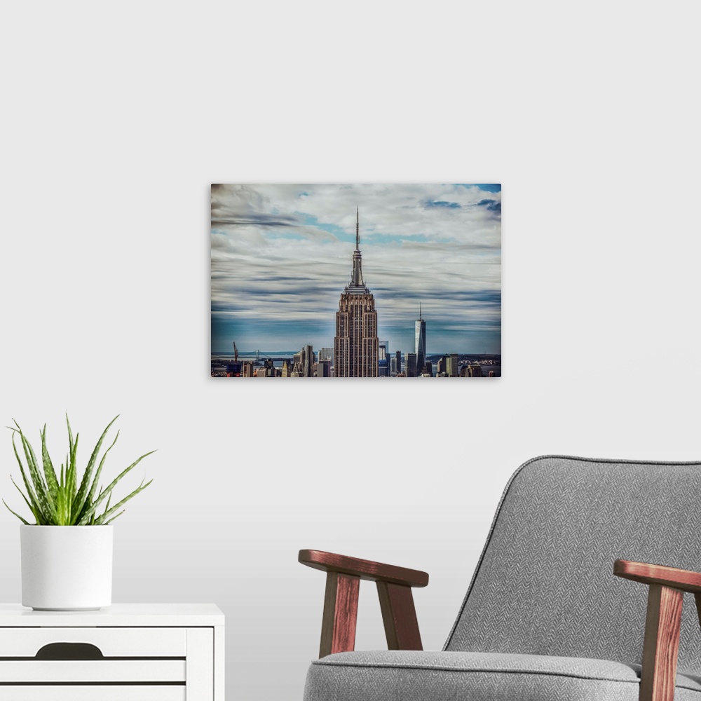 A modern room featuring Top view of the Empire State Building Broadcast Tower against dramatic clouds.