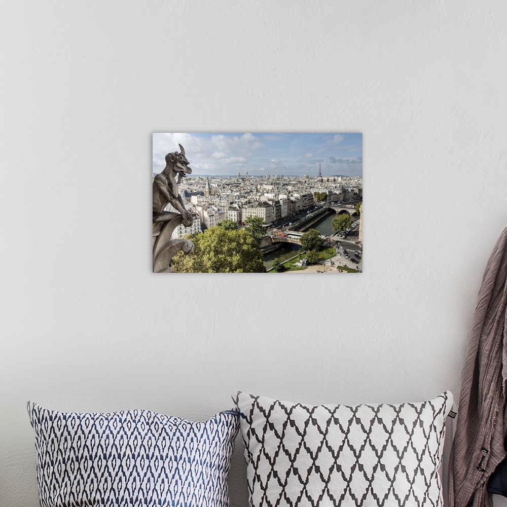 A bohemian room featuring Photograph of a gargoyle statue watching over the city of Paris.