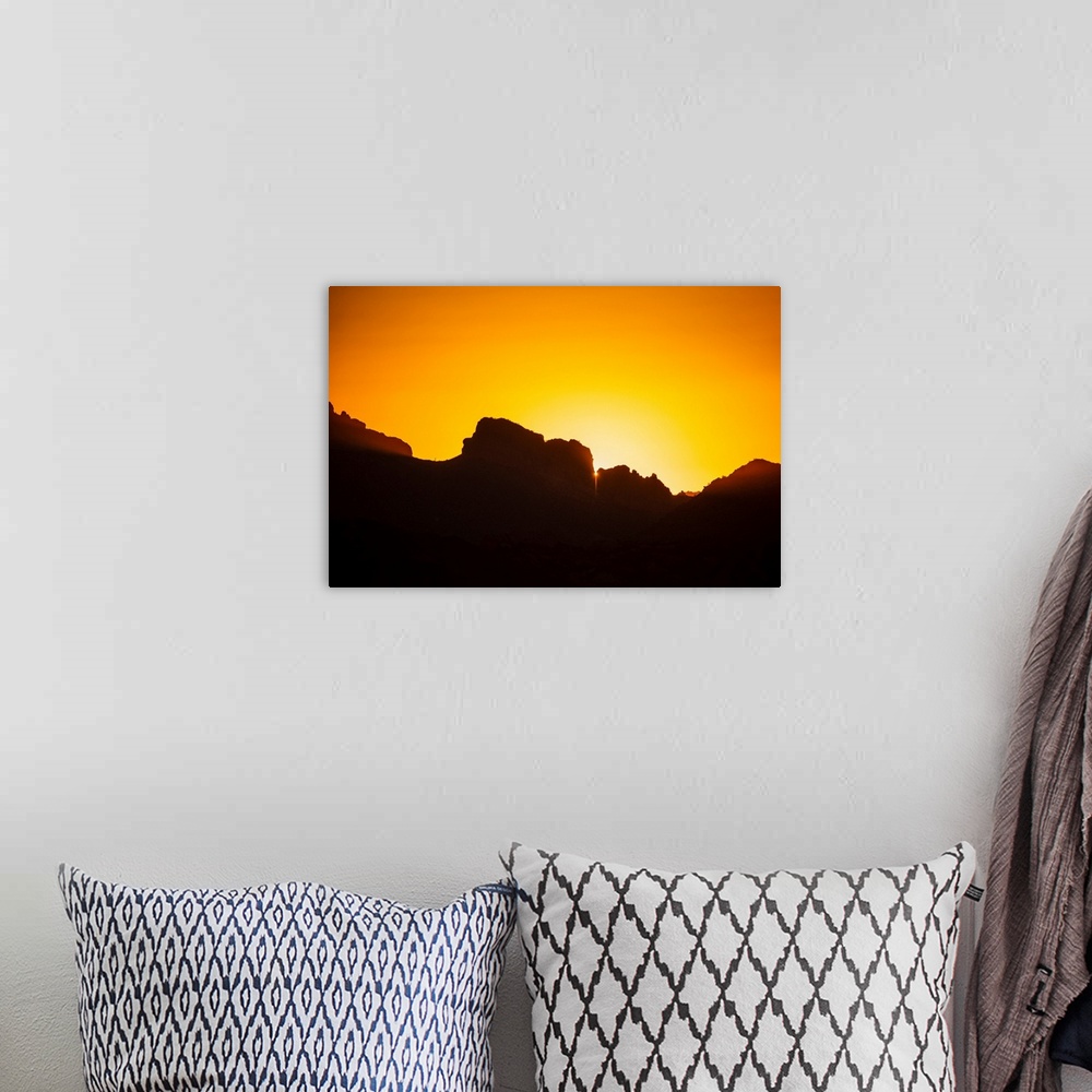 A bohemian room featuring Photo of a golden sunset over silhouetted rocks in Phoenix, Arizona.